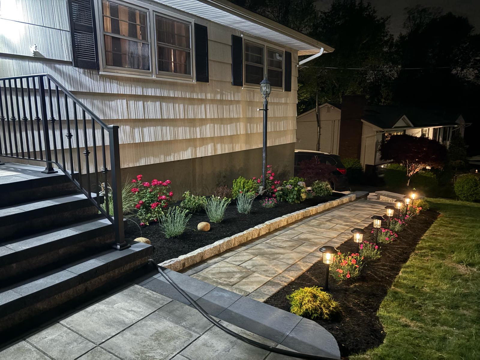 Paver patio with landscape lighting and garden bed installation